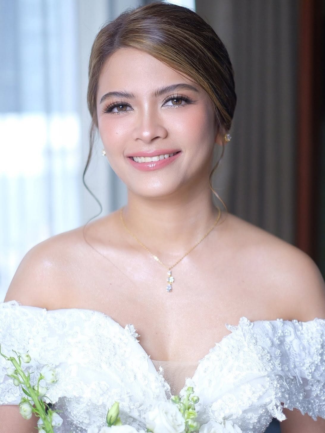 Smiling bride with a low updo and a pearl necklace